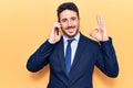 Young hispanic man wearing suit having conversation talking on the smartphone doing ok sign with fingers, smiling friendly Royalty Free Stock Photo