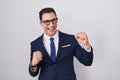 Young hispanic man wearing suit and tie very happy and excited doing winner gesture with arms raised, smiling and screaming for Royalty Free Stock Photo