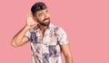 Young hispanic man wearing summer clothes smiling with hand over ear listening an hearing to rumor or gossip Royalty Free Stock Photo