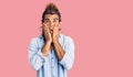 Young hispanic man wearing summer style afraid and shocked, surprise and amazed expression with hands on face Royalty Free Stock Photo