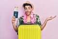 Young hispanic man wearing summer style and hawaiian lei holding passport and boarding pass celebrating achievement with happy Royalty Free Stock Photo