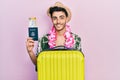 Young hispanic man wearing summer style and hawaiian lei holding passport and boarding pass looking positive and happy standing Royalty Free Stock Photo