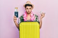 Young hispanic man wearing summer style and hawaiian lei holding passport and plane toy depressed and worry for distress, crying Royalty Free Stock Photo