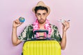 Young hispanic man wearing summer style and hawaiian lei holding world ball and plane toy depressed and worry for distress, crying Royalty Free Stock Photo