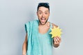 Young hispanic man wearing summer style holding yellow sun screaming proud, celebrating victory and success very excited with Royalty Free Stock Photo