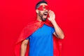 Young hispanic man wearing super hero costume shouting and screaming loud to side with hand on mouth