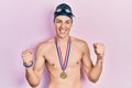 Young hispanic man wearing swimmer glasses and gold medal screaming proud, celebrating victory and success very excited with Royalty Free Stock Photo
