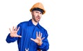 Young hispanic man wearing worker uniform afraid and terrified with fear expression stop gesture with hands, shouting in shock Royalty Free Stock Photo