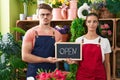 Young hispanic man a woman working at florist holding open sign smiling looking to the side and staring away thinking Royalty Free Stock Photo