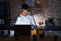 Young hispanic man working at the office at night angry and mad raising fist frustrated and furious while shouting with anger Royalty Free Stock Photo