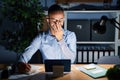 Young hispanic man working at the office at night laughing and embarrassed giggle covering mouth with hands, gossip and scandal Royalty Free Stock Photo