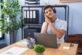 Young hispanic man working at the office wearing headphones sleeping tired dreaming and posing with hands together while smiling Royalty Free Stock Photo