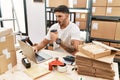 Young hispanic man working at small business ecommerce with laptop afraid and shocked with surprise and amazed expression, fear Royalty Free Stock Photo
