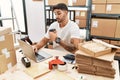 Young hispanic man working at small business ecommerce with laptop smiling looking to the side and staring away thinking Royalty Free Stock Photo