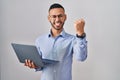 Young hispanic man working using computer laptop angry and mad raising fist frustrated and furious while shouting with anger Royalty Free Stock Photo