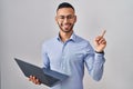 Young hispanic man working using computer laptop with a big smile on face, pointing with hand finger to the side looking at the Royalty Free Stock Photo