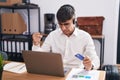 Young hispanic man working using computer laptop holding credit card angry and mad raising fist frustrated and furious while Royalty Free Stock Photo