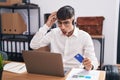 Young hispanic man working using computer laptop holding credit card crazy and scared with hands on head, afraid and surprised of Royalty Free Stock Photo