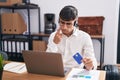 Young hispanic man working using computer laptop holding credit card pointing to the eye watching you gesture, suspicious Royalty Free Stock Photo