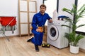 Young hispanic man working on washing machine thinking attitude and sober expression looking self confident Royalty Free Stock Photo