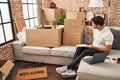 Young hispanic man writing on book sitting on sofa at new home Royalty Free Stock Photo