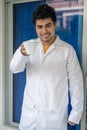 Young Hispanic medical student wearing a medical robe and holding a cup of coffee in a hospital