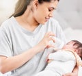 Young hispanic mother feeding her newborn baby a milk bottle and bonding with her. Little baby asleep in her mothers