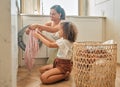 Young hispanic mother and her daughter sorting dirty laundry in the washing machine at home. Adorable little girl and Royalty Free Stock Photo