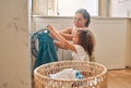 Young hispanic mother and her daughter sorting dirty laundry in the washing machine at home. Adorable little girl Royalty Free Stock Photo