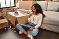 Young hispanic mother and kid sitting on the floor at new home using laptop smiling happy pointing with hand and finger Royalty Free Stock Photo