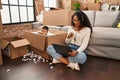 Young hispanic mother and kid sitting on the floor at new home using laptop smiling happy pointing with hand and finger to the Royalty Free Stock Photo