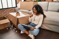 Young hispanic mother and kid sitting on the floor at new home using laptop smiling happy and positive, thumb up doing excellent Royalty Free Stock Photo