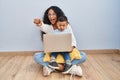 Young hispanic mother and kid using computer laptop sitting on the floor pointing to you and the camera with fingers, smiling Royalty Free Stock Photo