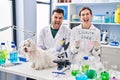 Young hispanic people working at scientist laboratory with dog smiling and laughing hard out loud because funny crazy joke Royalty Free Stock Photo