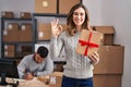 Young hispanic people working at small business ecommerce holding gift doing ok sign with fingers, smiling friendly gesturing Royalty Free Stock Photo