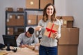 Young hispanic people working at small business ecommerce holding gift smiling happy pointing with hand and finger Royalty Free Stock Photo