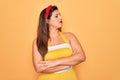 Young hispanic pin up woman wearing fashion sexy 50s style over yellow background looking to the side with arms crossed convinced Royalty Free Stock Photo