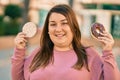 Young hispanic plus size woman smiling happy holding rice cake and donut at the city Royalty Free Stock Photo