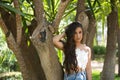 Young, Hispanic, pretty, brunette, young woman in a daisy shirt and jeans, looking at the camera calm and relaxed, leaning against Royalty Free Stock Photo