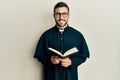 Young hispanic priest man holding bible smiling with a happy and cool smile on face Royalty Free Stock Photo