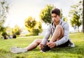 Runner in the city resting in park tying shoelaces. Royalty Free Stock Photo