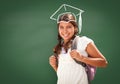 Young Hispanic Student Girl Wearing Backpack Front Of Blackboard with Fireman Helmet Drawn In Chalk Over Head