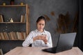 Young Hispanic student holding smartphone studying on laptop, using mobile learning classes tech apps. Teenage girl Royalty Free Stock Photo