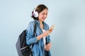 Young Hispanic student woman listen music with headphones and holding computer over isolated blue background Royalty Free Stock Photo