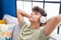 Young hispanic teenager listening to music relaxed on sofa at home