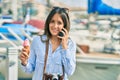 Young hispanic tourist woman talking on the smartphone and eating ice cream at the port Royalty Free Stock Photo