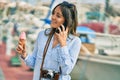 Young hispanic tourist woman talking on the smartphone and eating ice cream at the port Royalty Free Stock Photo