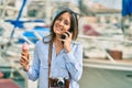 Young hispanic tourist woman talking on the smartphone and eating ice cream at the port Royalty Free Stock Photo