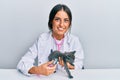 Young hispanic veterinary girl examining cat using stethoscope at the clinic