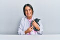 Young hispanic veterinary girl examining cat using stethoscope at the clinic